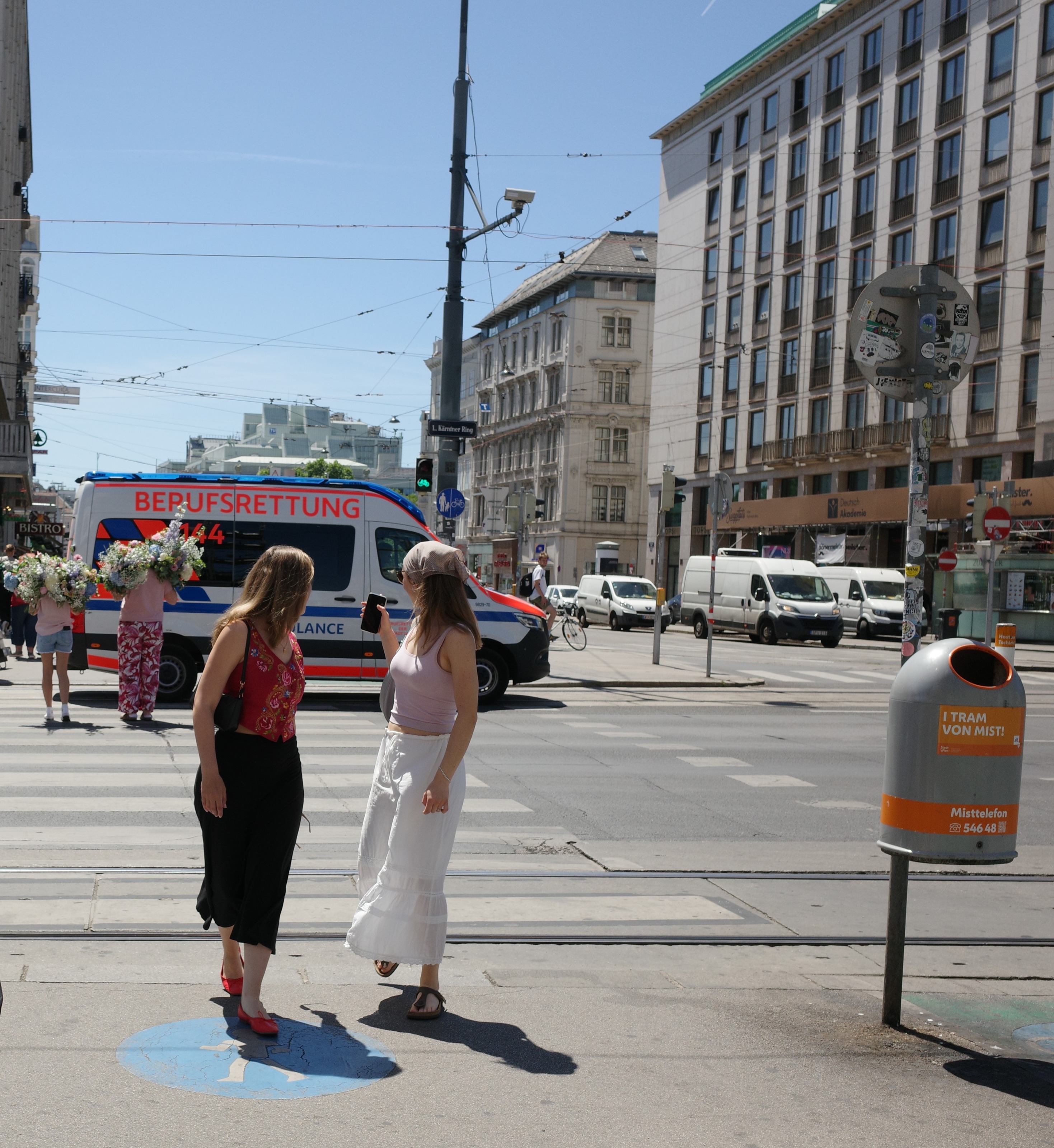 Street corner with an ambulance passing behind two pedestrians