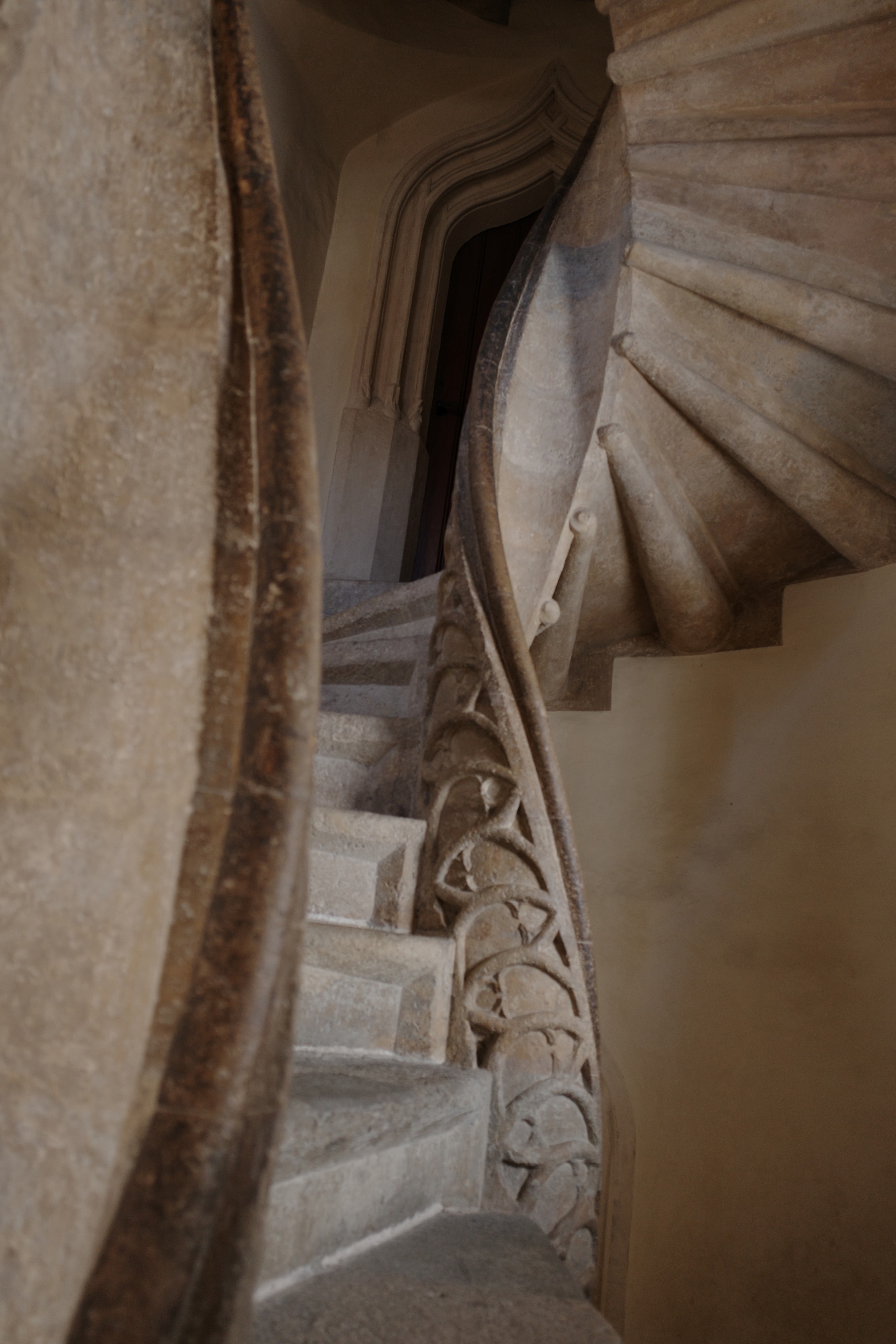 A carved stone double spiral staircase seen through the gap between its two flights