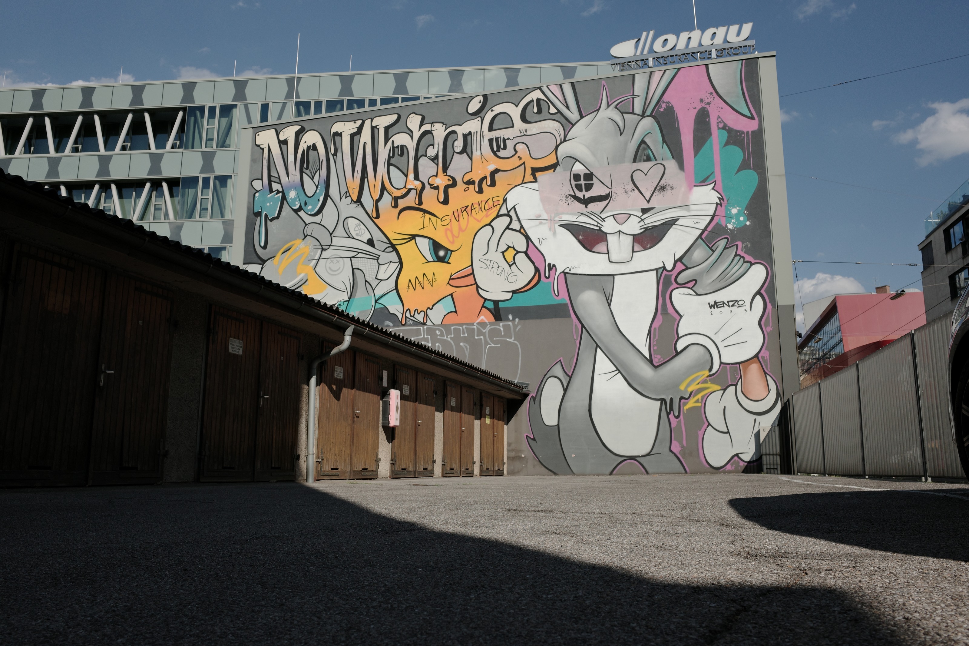 A cartoon rabbit mural reading No Worries painted across the end of a building above a row of garages